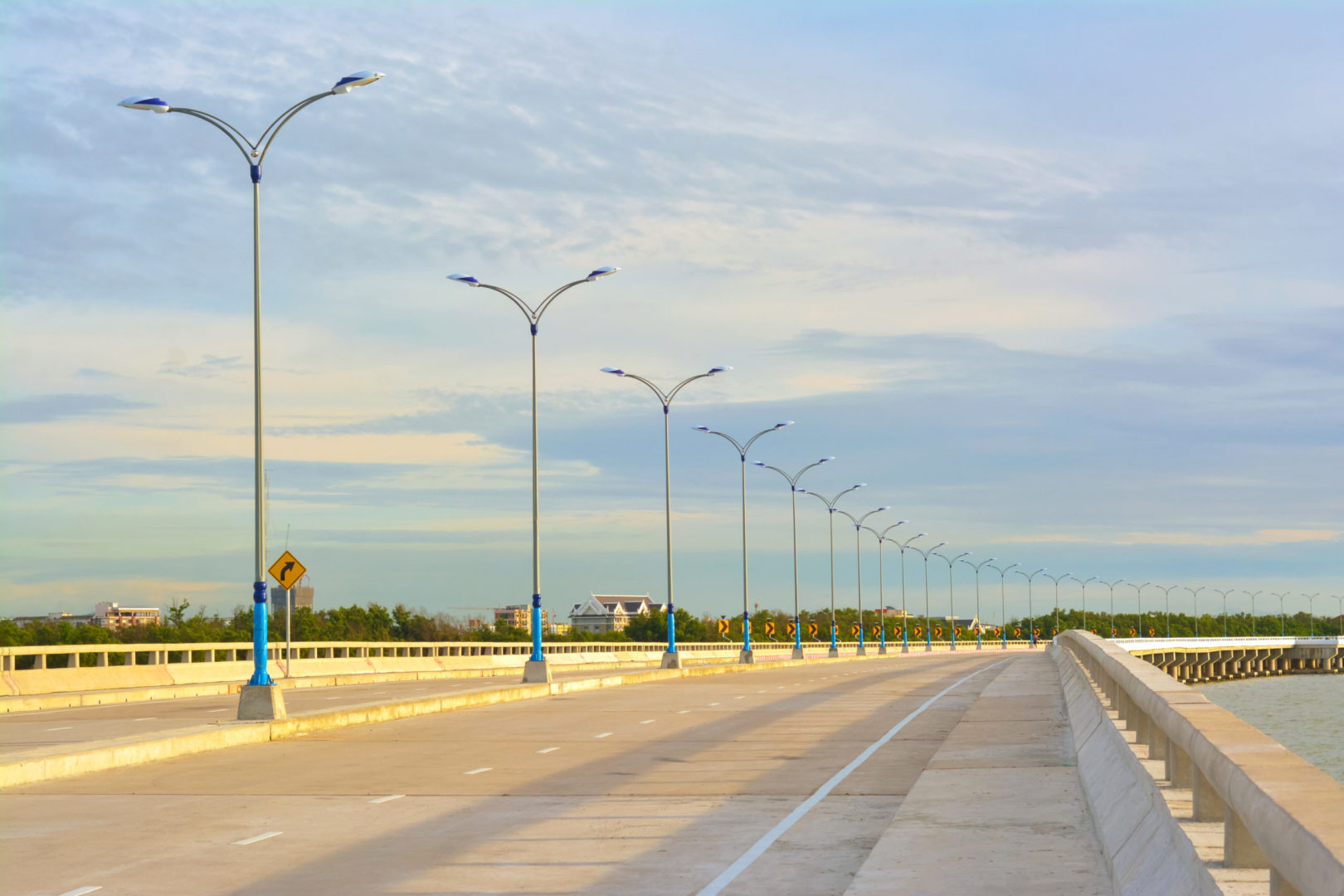 An empty highway bridge with a row of light poles lining the center median.