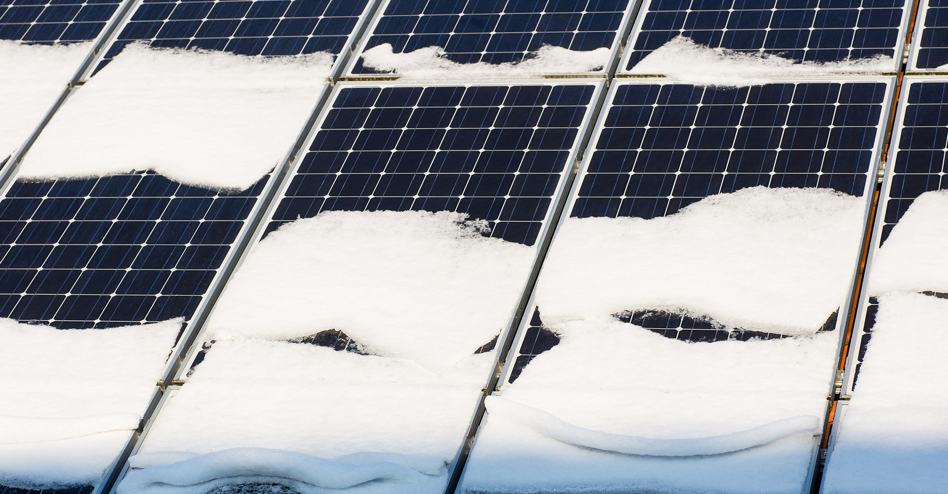 A Close-up view of an array of solar panels with snow sitting on top.