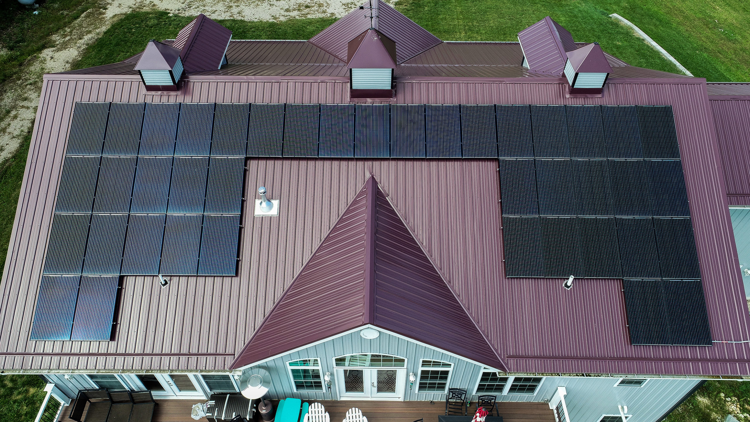 Maroon metal roof on a house with solar on top